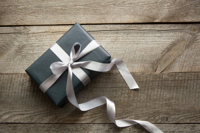 A beautifully wrapped dark gift box with a ribbon on a wooden surface.