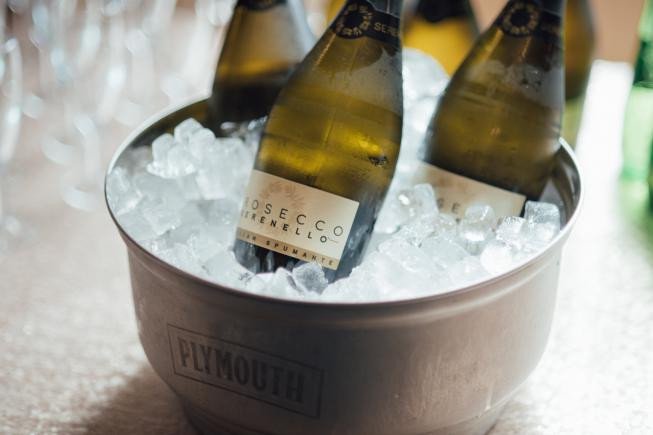 Three chilled wine bottles sitting in a metal bucket filled with ice.