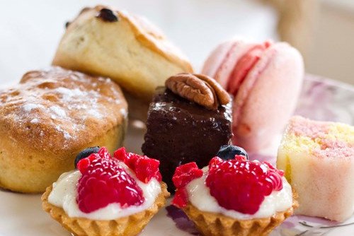 Assorted small desserts including tarts, cakes, and macarons arranged on a plate