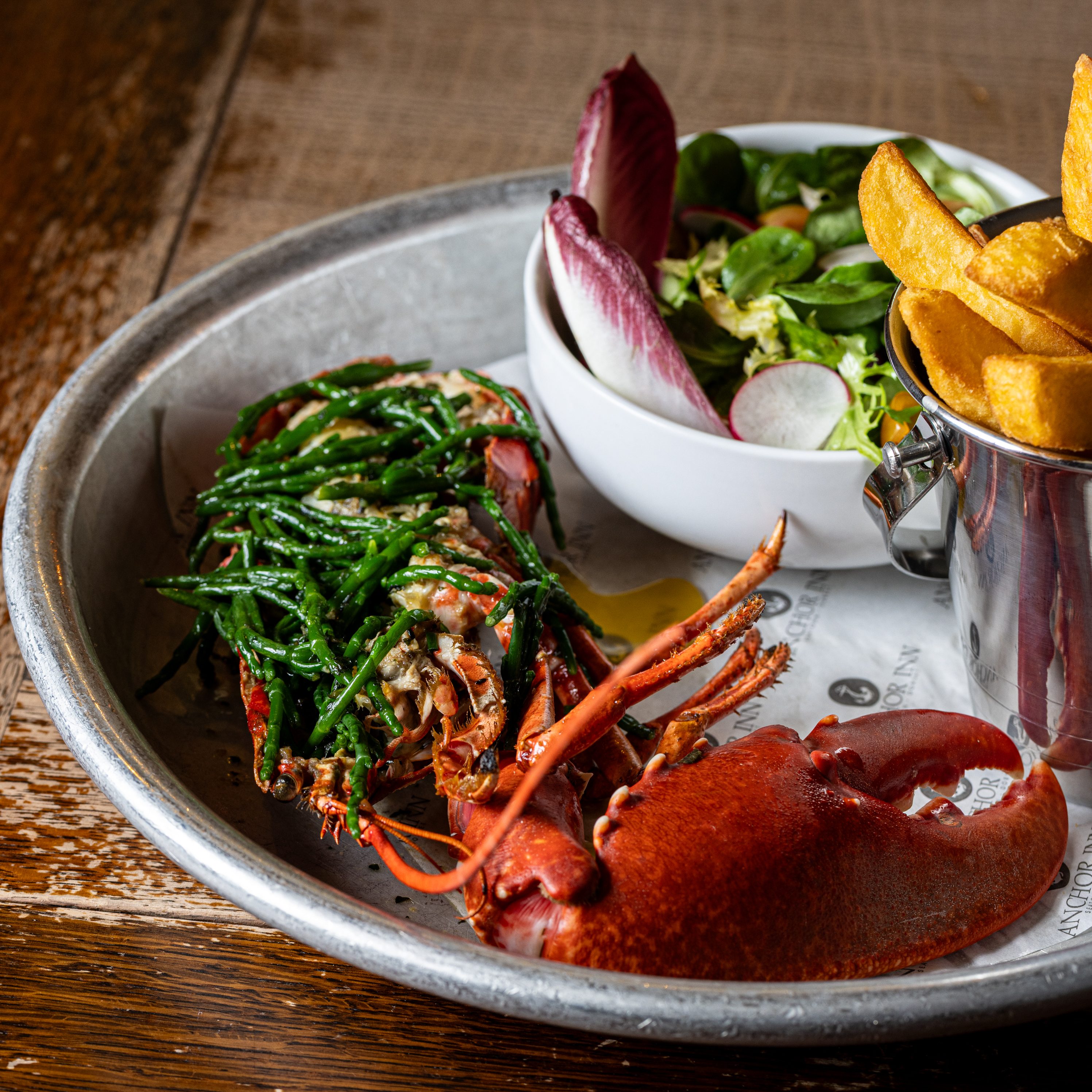 A plate featuring grilled lobster, salad, and fries