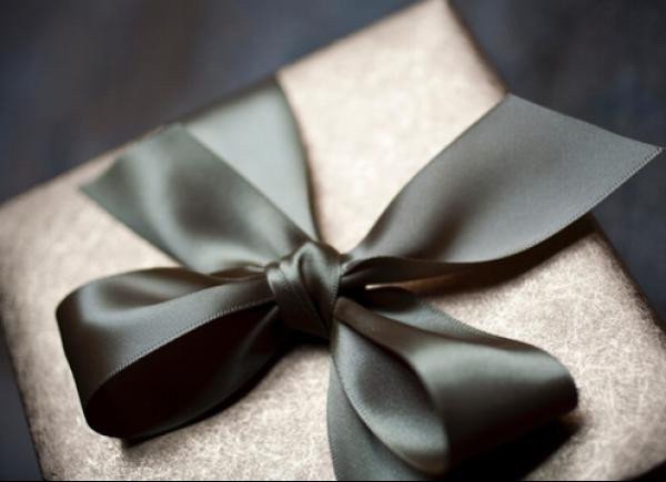 A wrapped gift box tied with a large black ribbon bow.