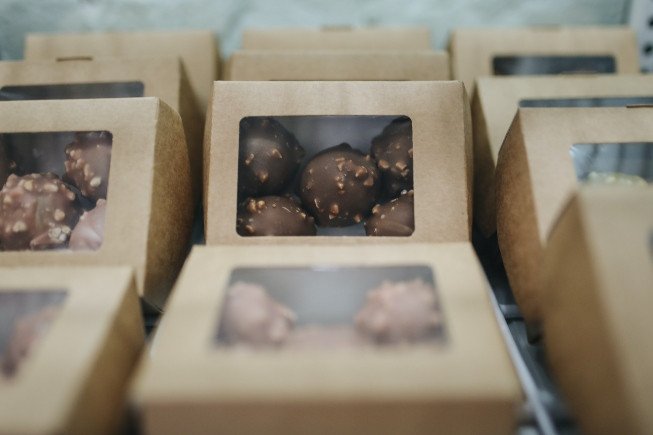 Small cardboard boxes with clear windows showing chocolate truffles inside.