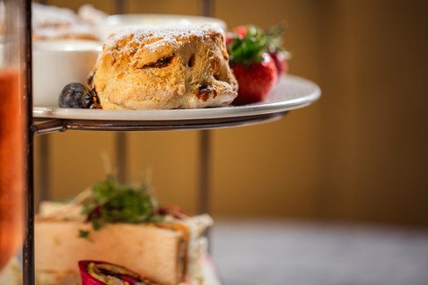 A powdered pastry on a tiered dessert stand with strawberries and other sweets in the background.