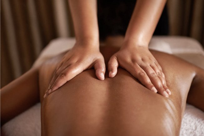 Hands giving a massage to a person's back on a treatment table