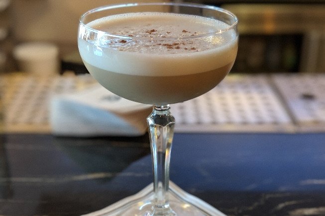 A frothy cocktail served in a stemmed coupe glass.