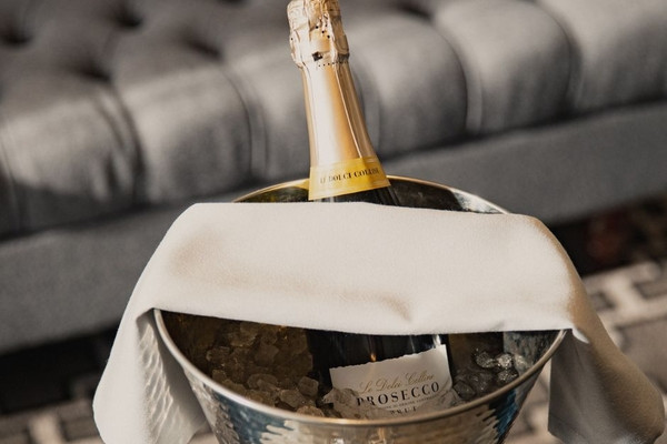 A bottle of Prosecco resting in an ice bucket with a white cloth.