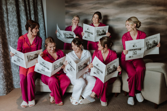 Bridal party in matching pajamas reading newspapers together