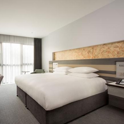 A spacious and modern hotel room with a large bed and desk.