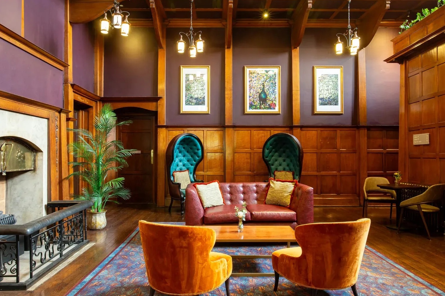 A cozy lounge with a red sofa, orange chairs, and wooden decor