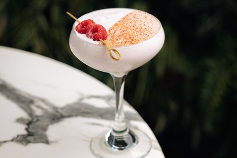 A cocktail garnished with raspberries and a sprinkle of spice.