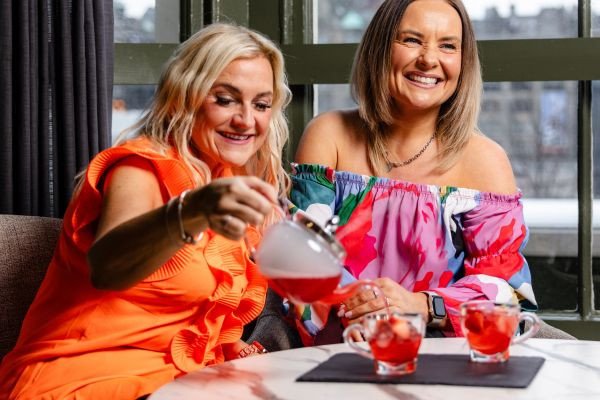 Two women pouring and enjoying drinks at a stylish venue.