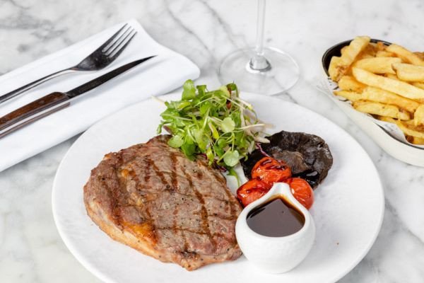 A plate featuring grilled steak, salad, tomatoes, and fries.