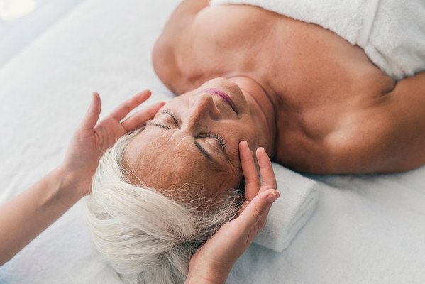 A woman receiving a facial massage in a serene setting