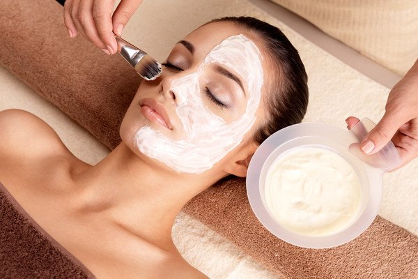 Woman receiving a facial treatment with cream applied to her face