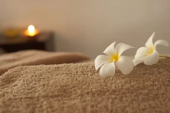 Two white flowers on a brown towel in a serene spa environment