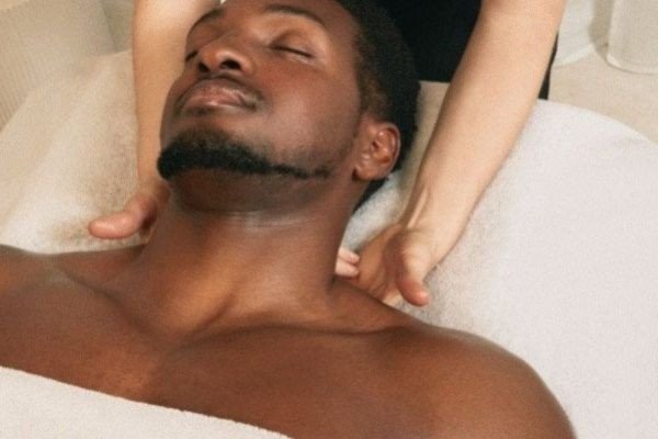 A man receiving a massage with eyes closed, showing relaxation.
