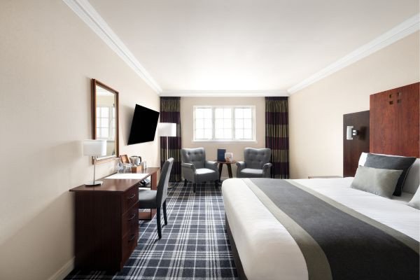 A spacious hotel room with a bed, seating area, and desk.