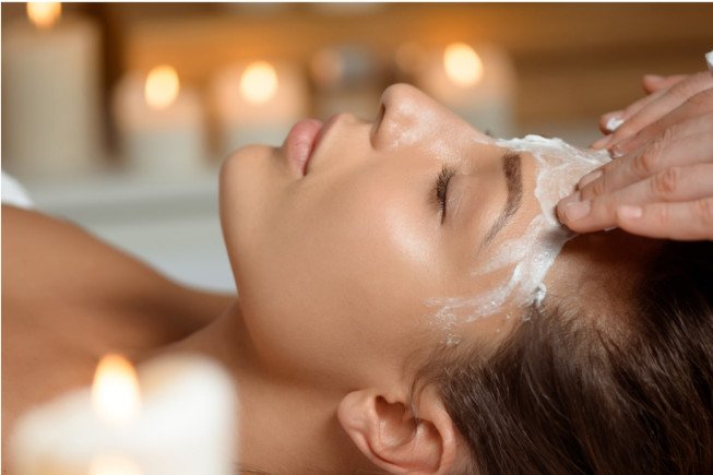 Woman receiving a facial treatment with candles in the background